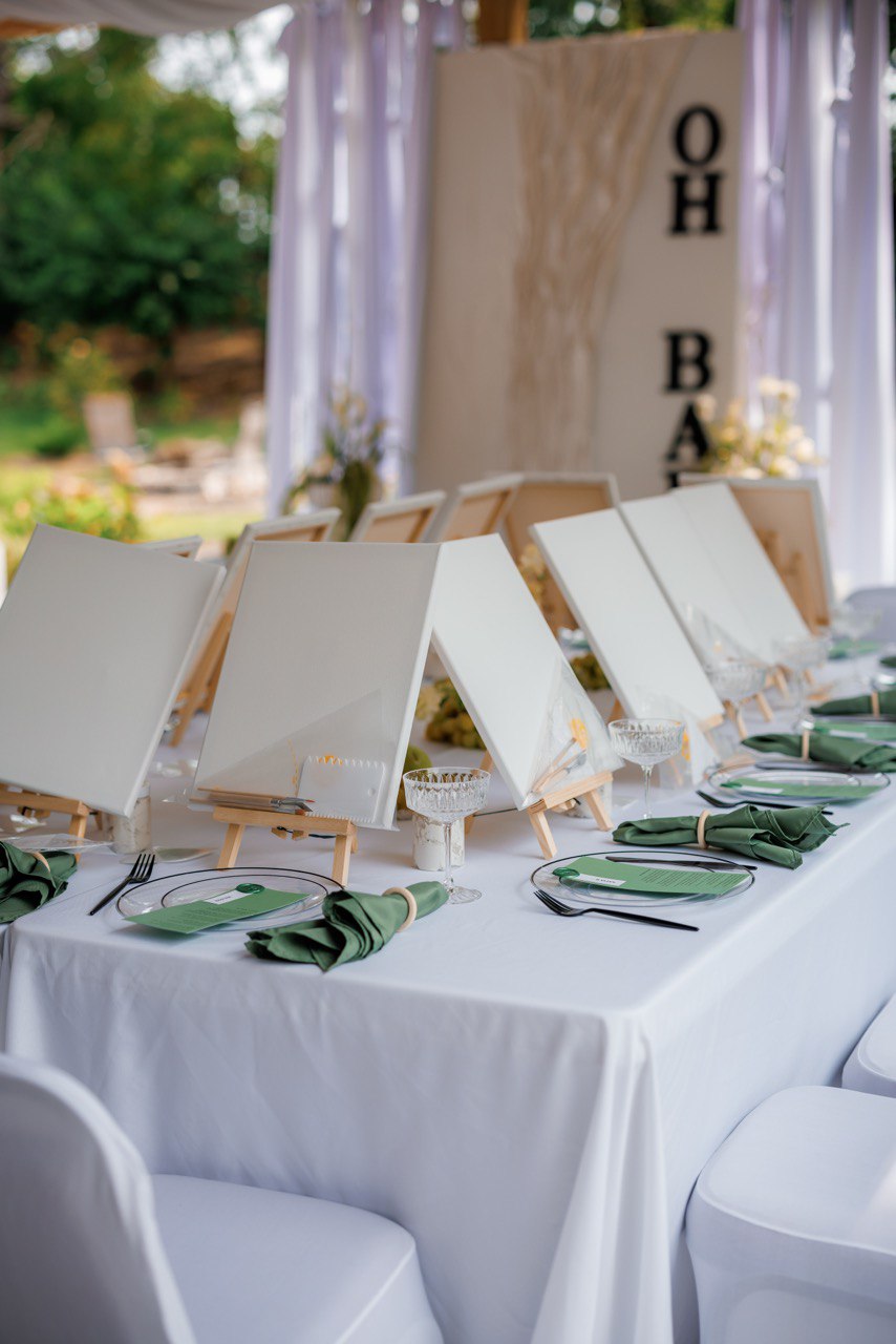Kids painting party table with easels, canvases and crystal cups on white linens