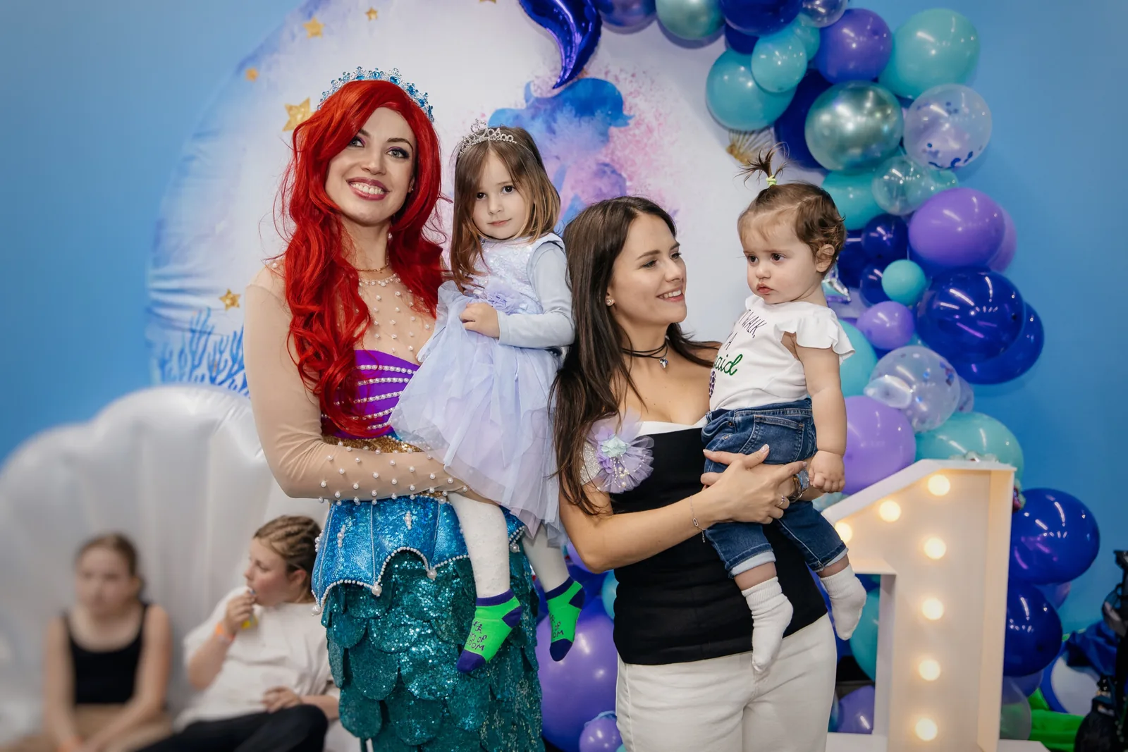 Mermaid entertainer posing with children at an under-the-sea themed party