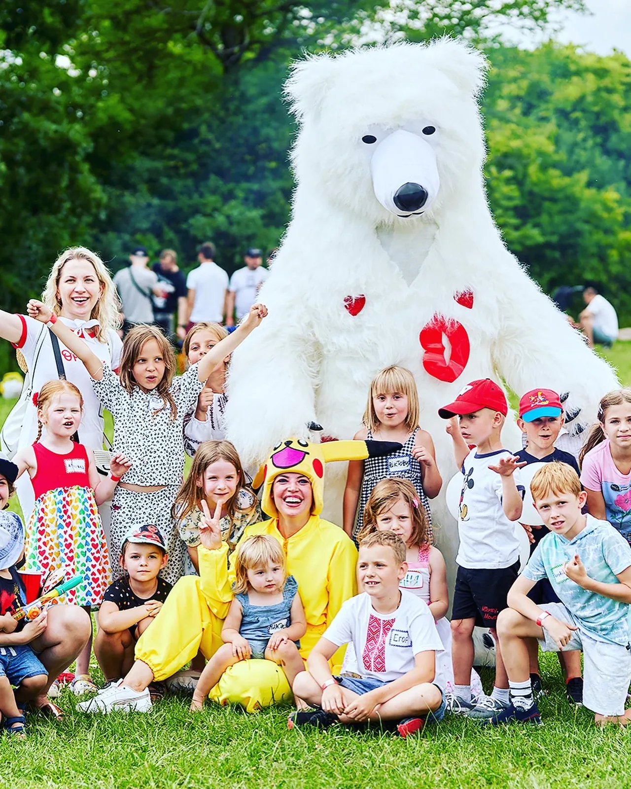 Children posing with a giant bear mascot at an outdoor event