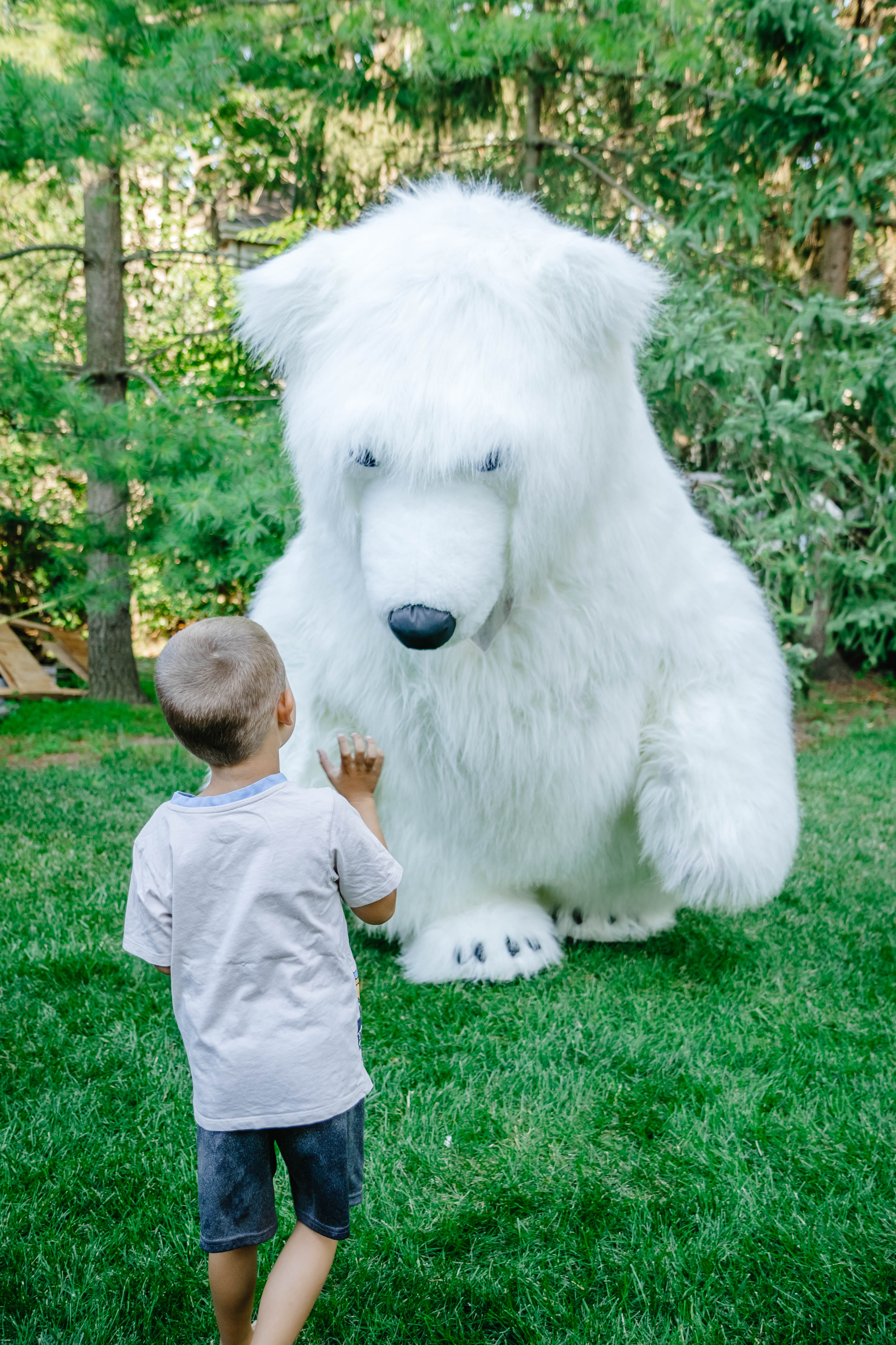 Young boy meeting a friendly giant bear mascot outdoors