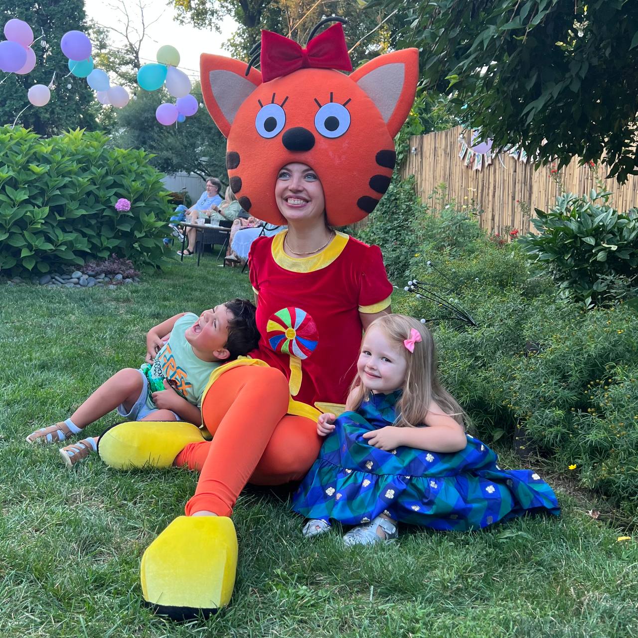 Candy Cat costumed entertainer sitting with children at a birthday party