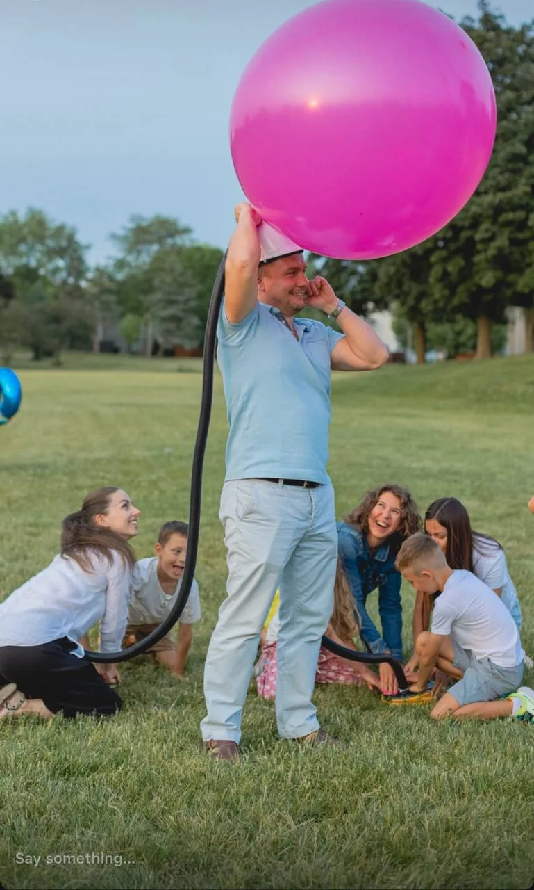 Man wearing a helmet with a giant balloon being inflated at a kids event