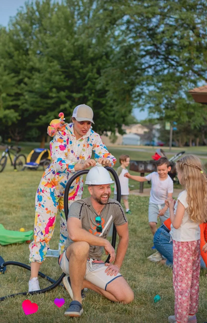 Entertainer placing a tube on a man's helmet at a playful outdoor activity