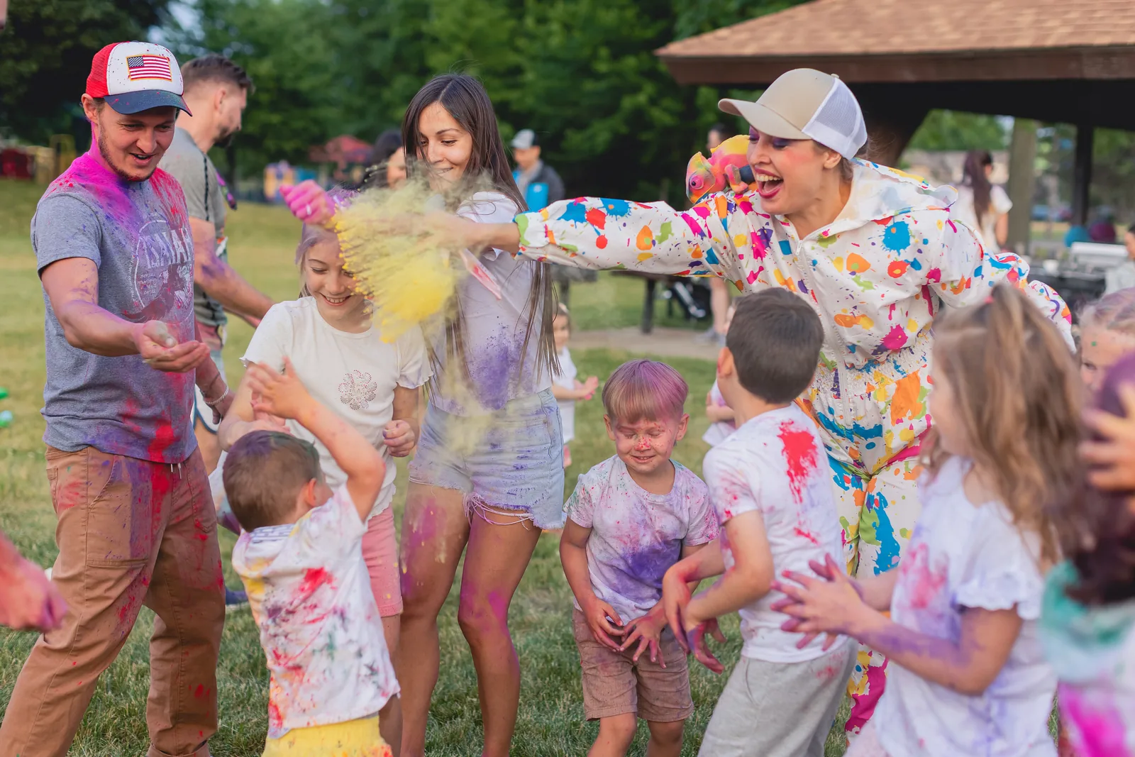 Entertainer throwing colored powder at children during a fun outdoor event