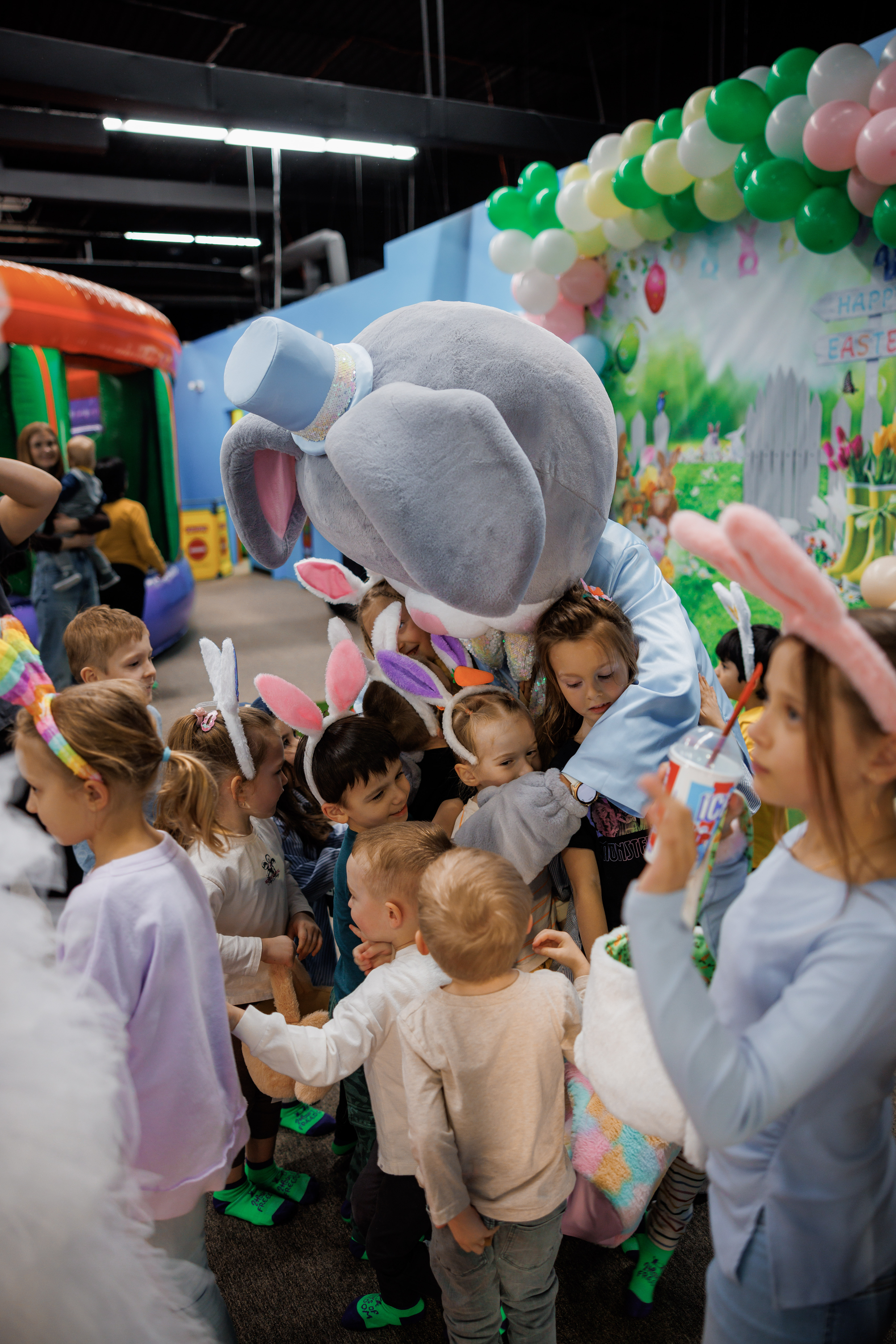 Easter bunny mascot hugging a group of children at a party