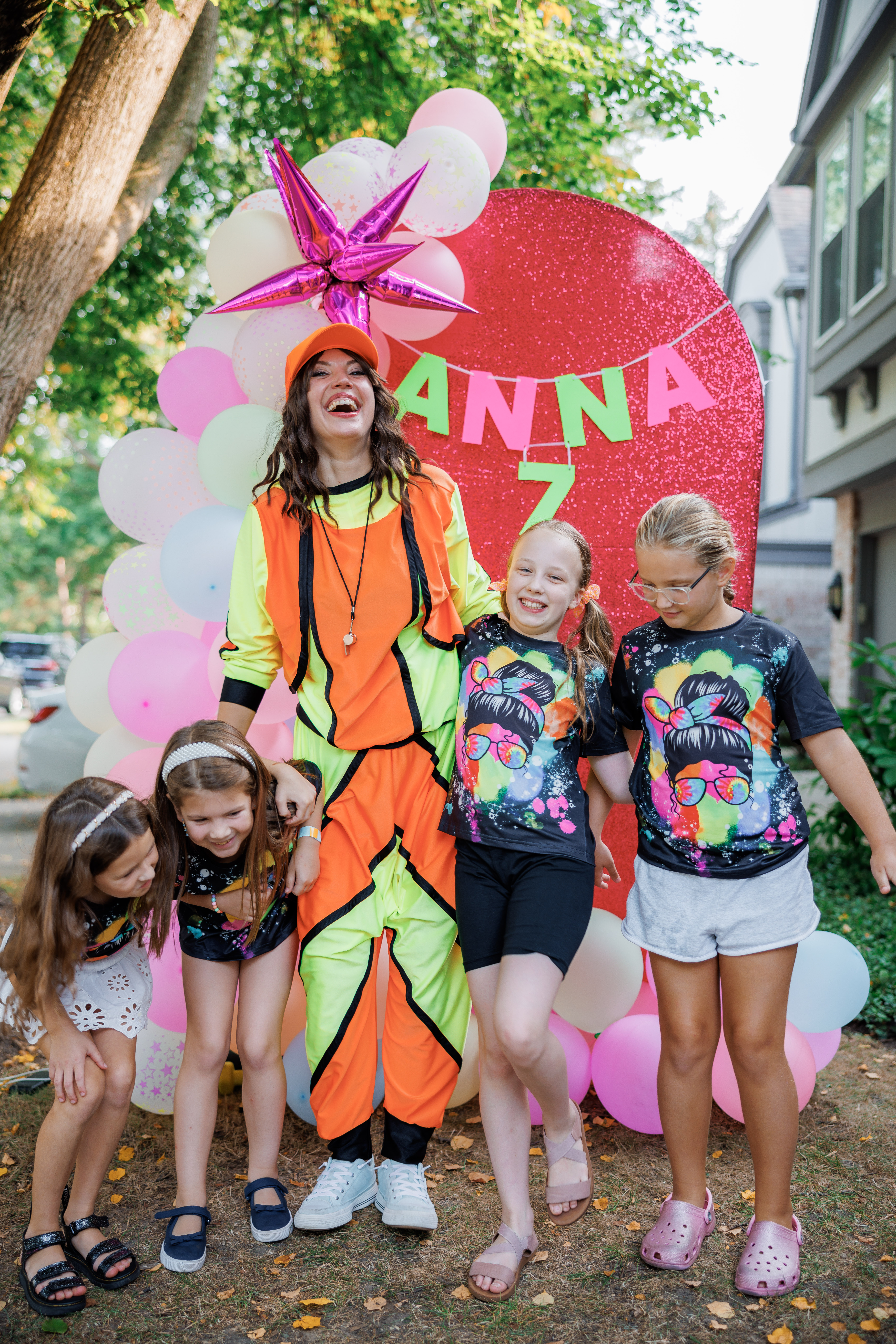 Neon party host posing with kids during a glow-themed birthday event