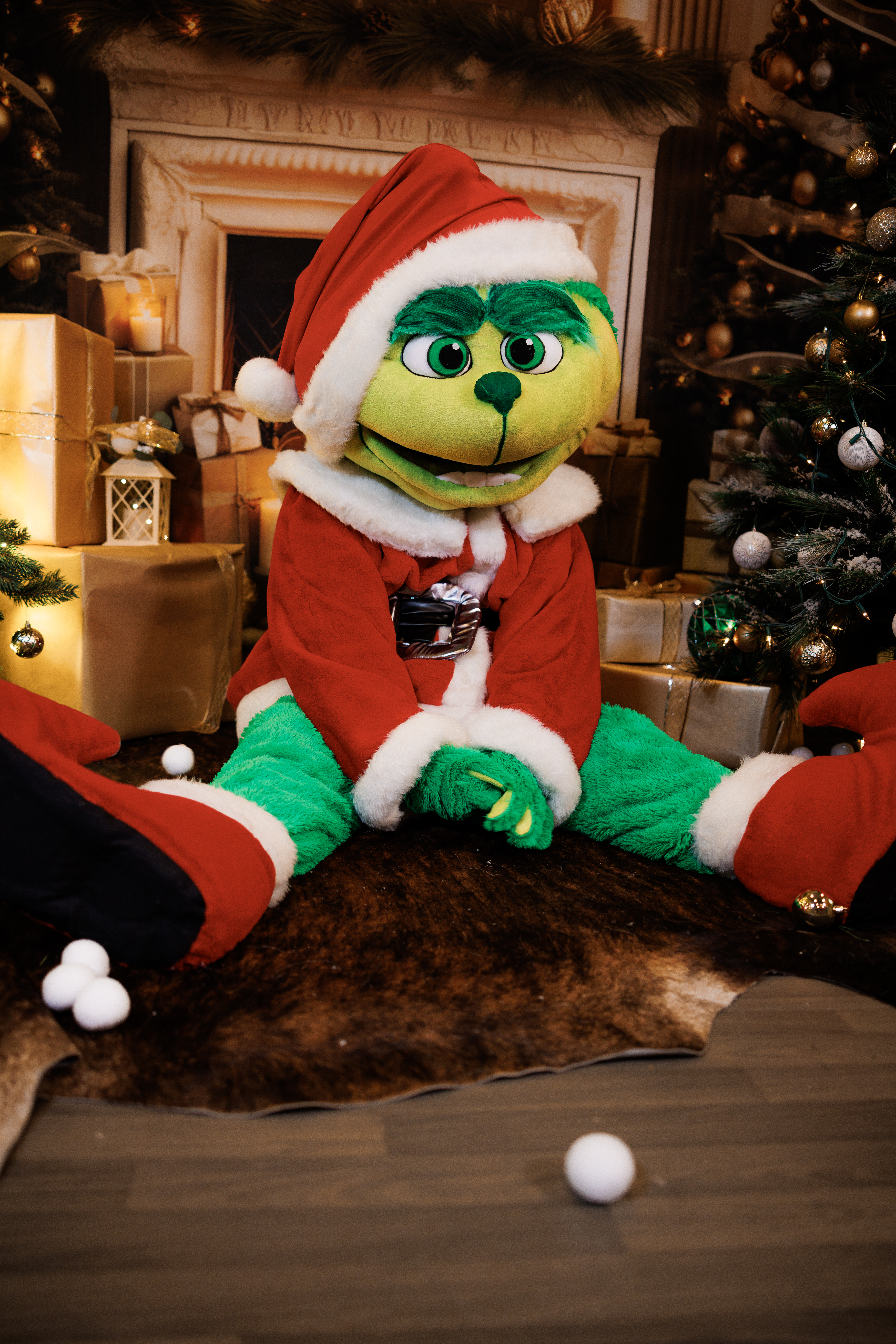 Grinch character dressed in a Santa costume at a Christmas-themed setup