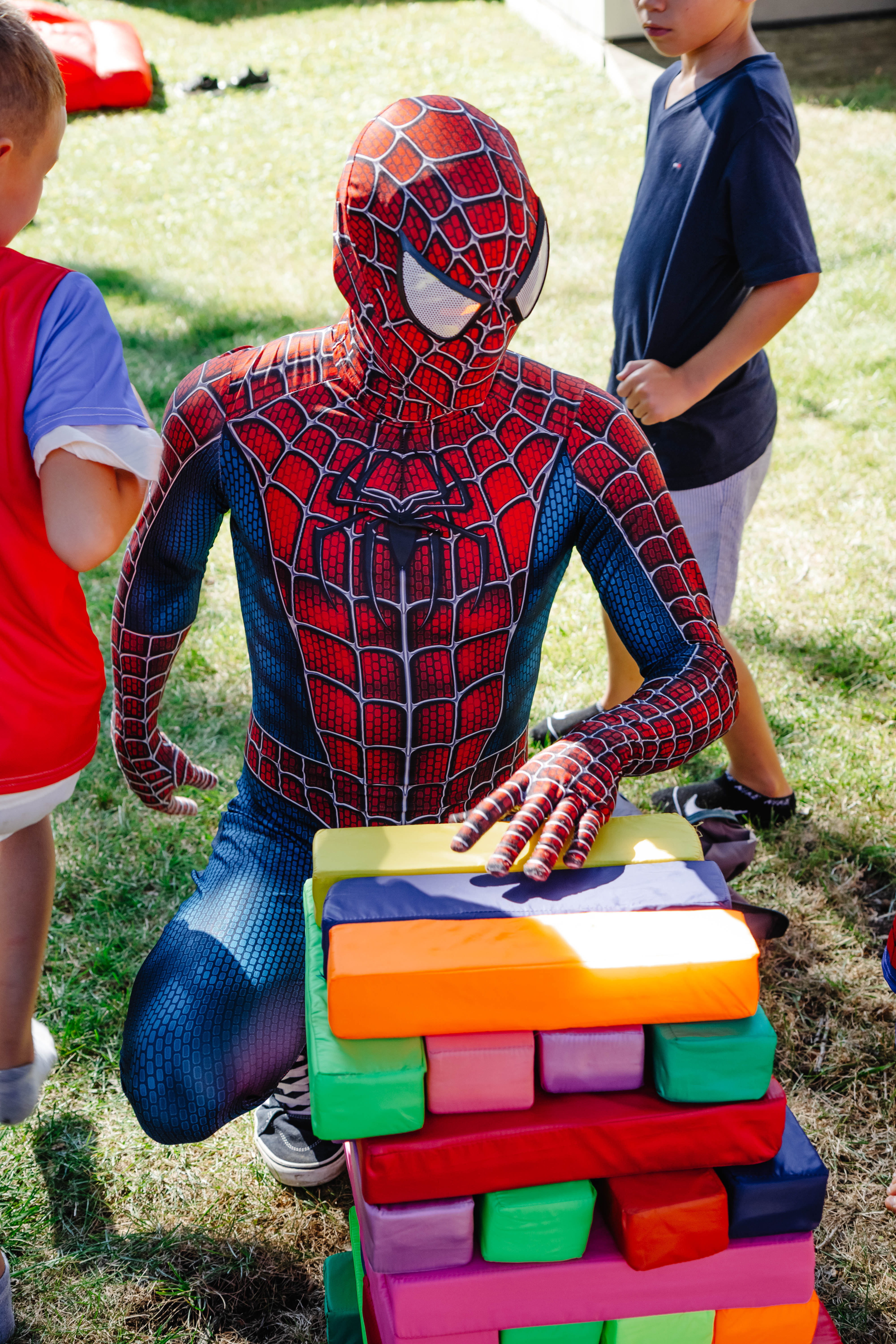 Spiderman posing heroically while kids run around