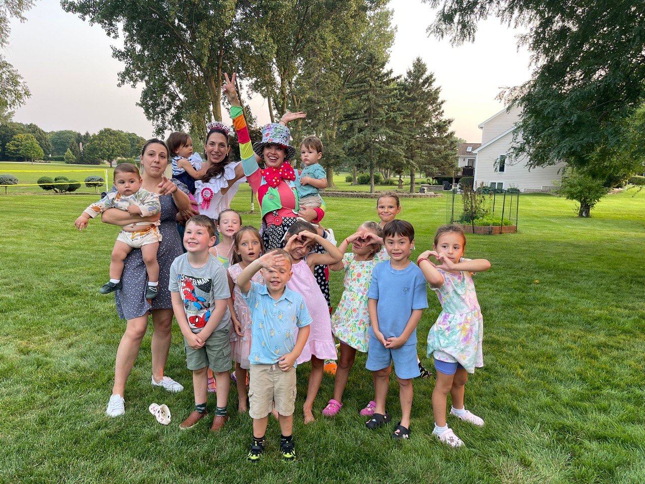 Kids and parents posing with a clown entertainer at an outdoor event