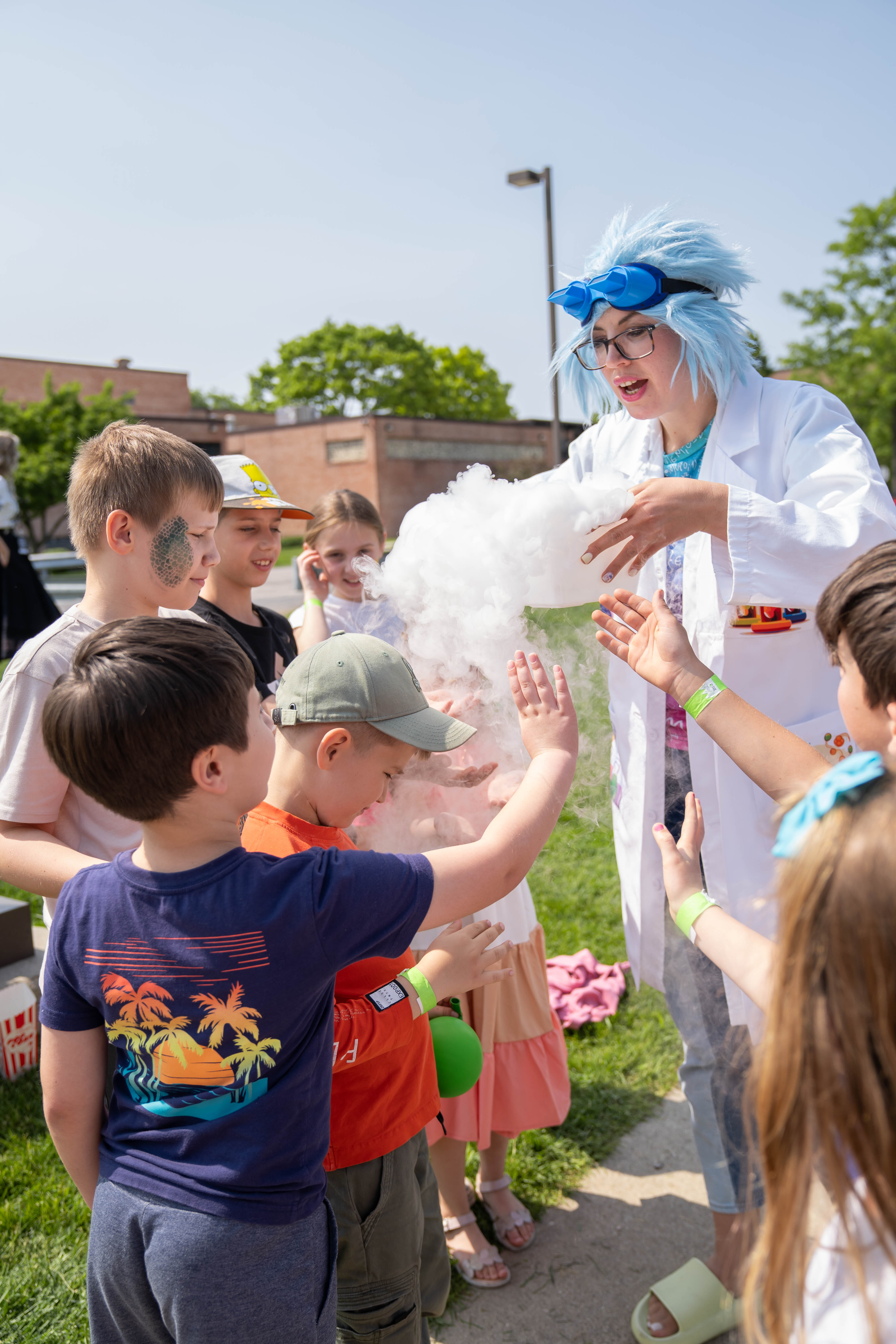 Kids gathered around a performer doing a science experiment with smoke